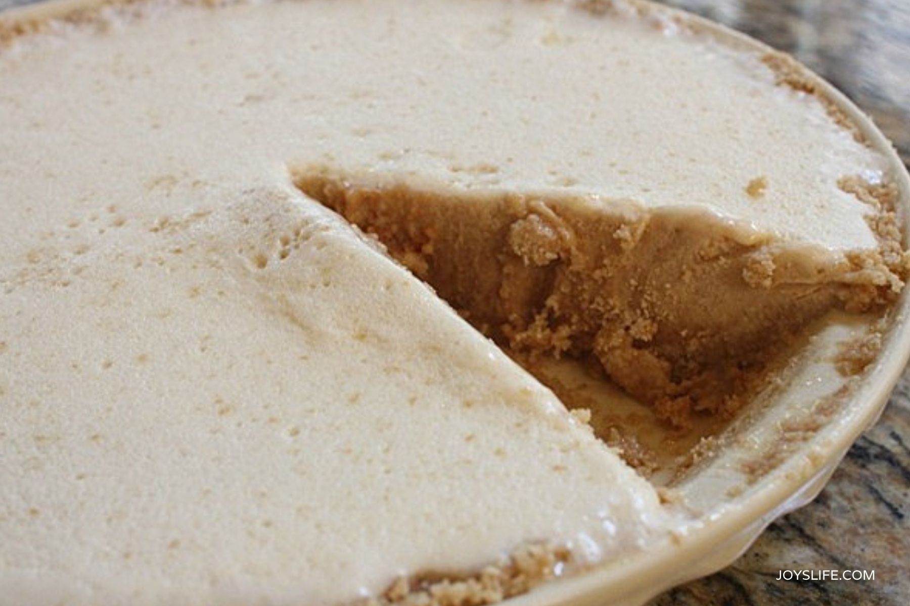 whole peanut butter ice cream pie with a slice removed showing creamy filling and graham cracker crust from joyslife.com