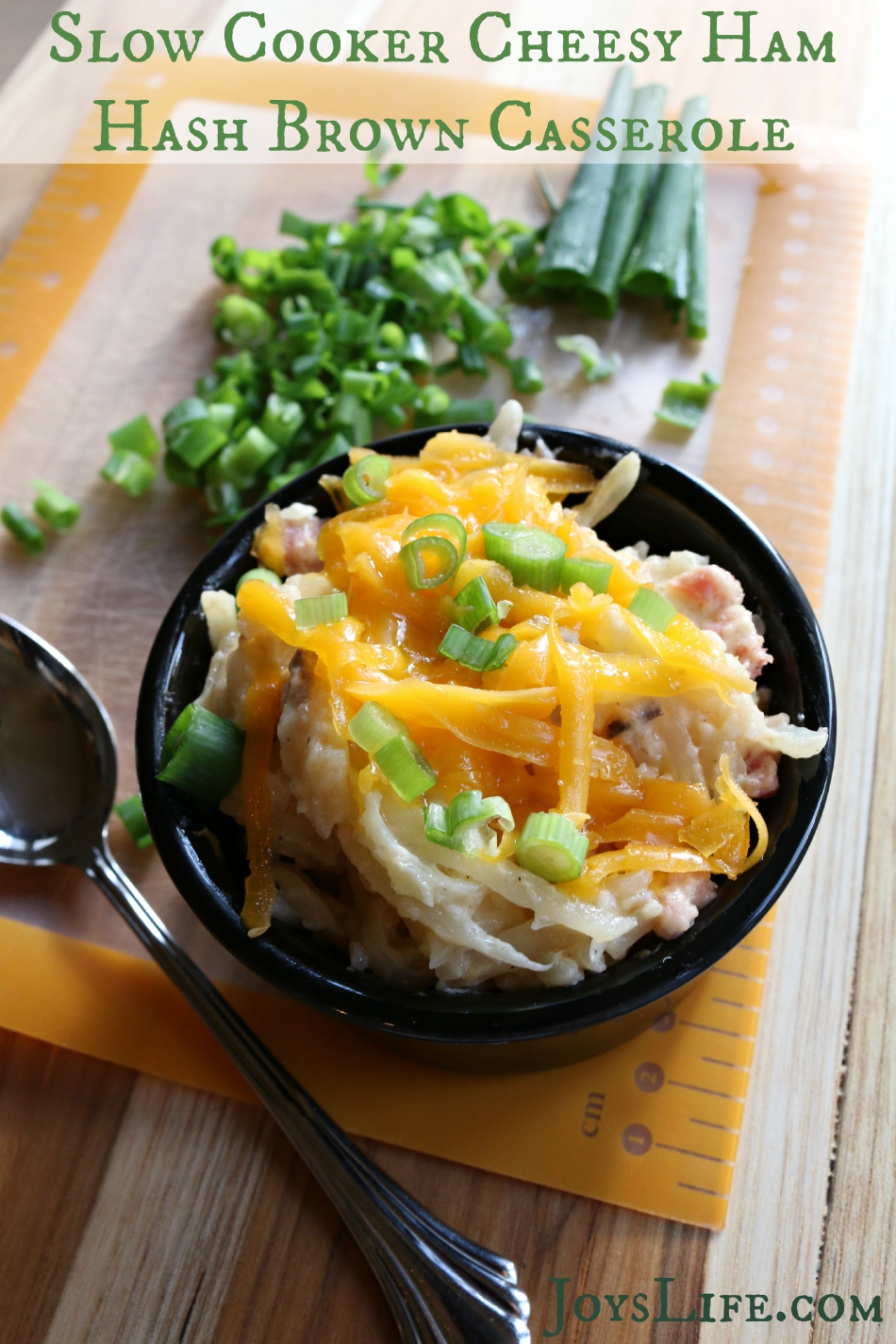 Slow cooker cheesy ham hash brown casserole topped with melted cheese and ham in a serving bowl.