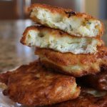Crispy zucchini fritters stacked on a plate, golden brown and cheesy