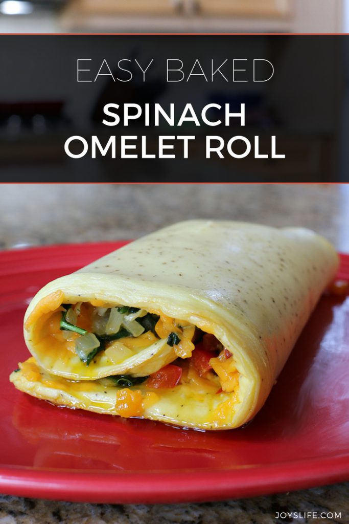 Easy baked spinach omelet roll sliced on a red plate, filled with spinach, peppers, onions, and cheddar cheese.