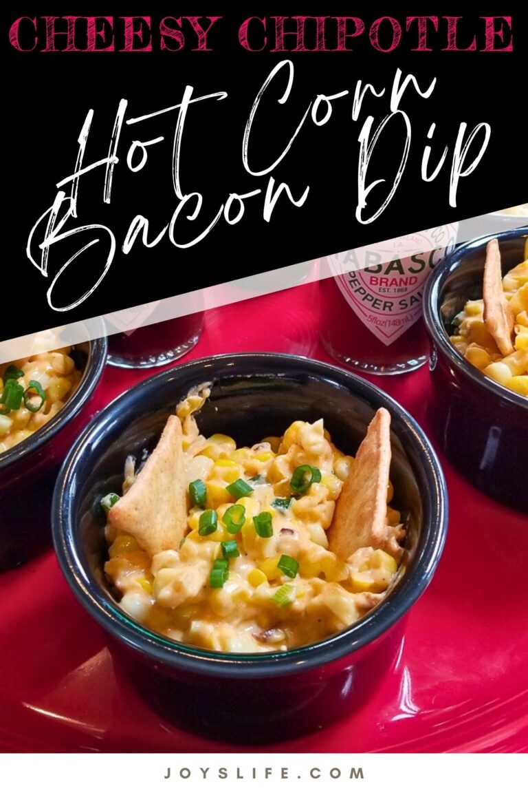 Cheesy chipotle hot corn bacon dip in a black ramekin, garnished with green onions and served with pita chips.