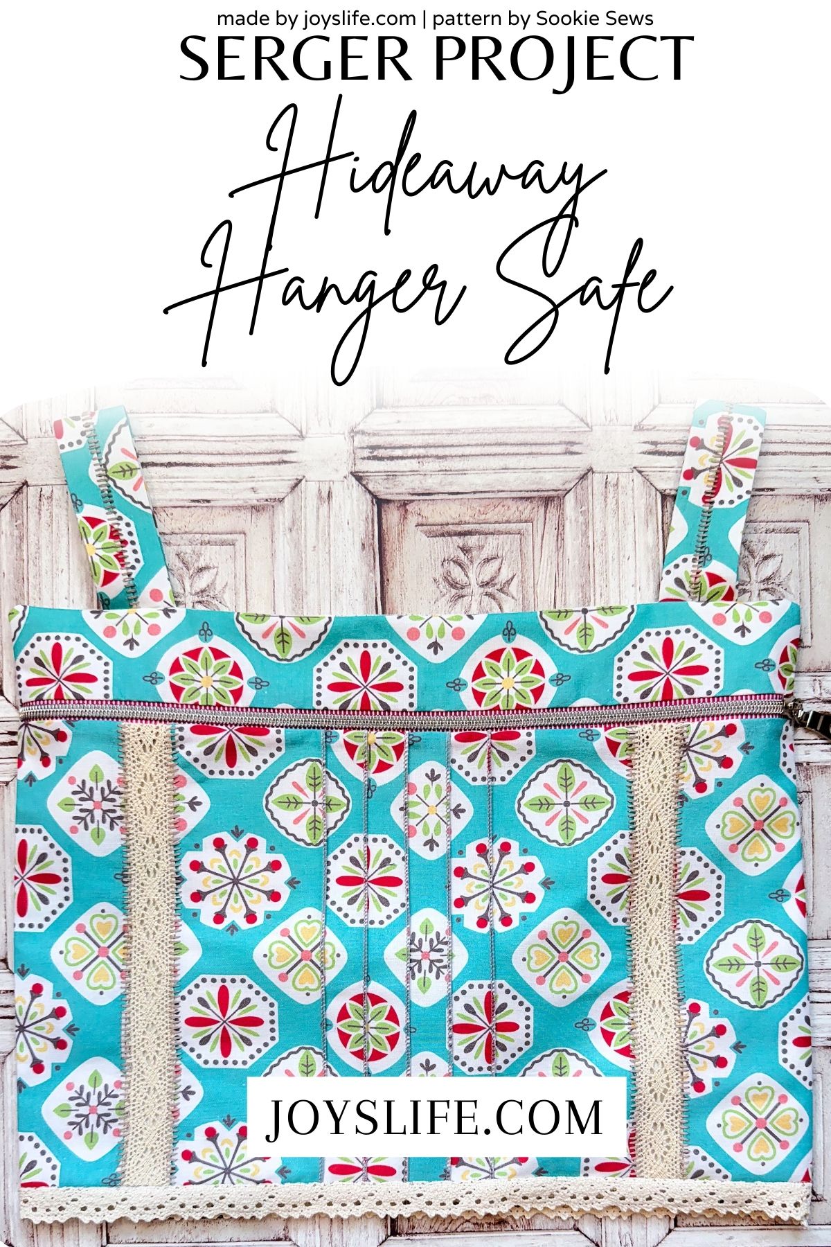 Colorful Hideaway Hanger Safe sewing project made from teal geometric fabric with red and green floral trim, lace insertion, and a zipper closure. Displayed against a rustic white wooden background.