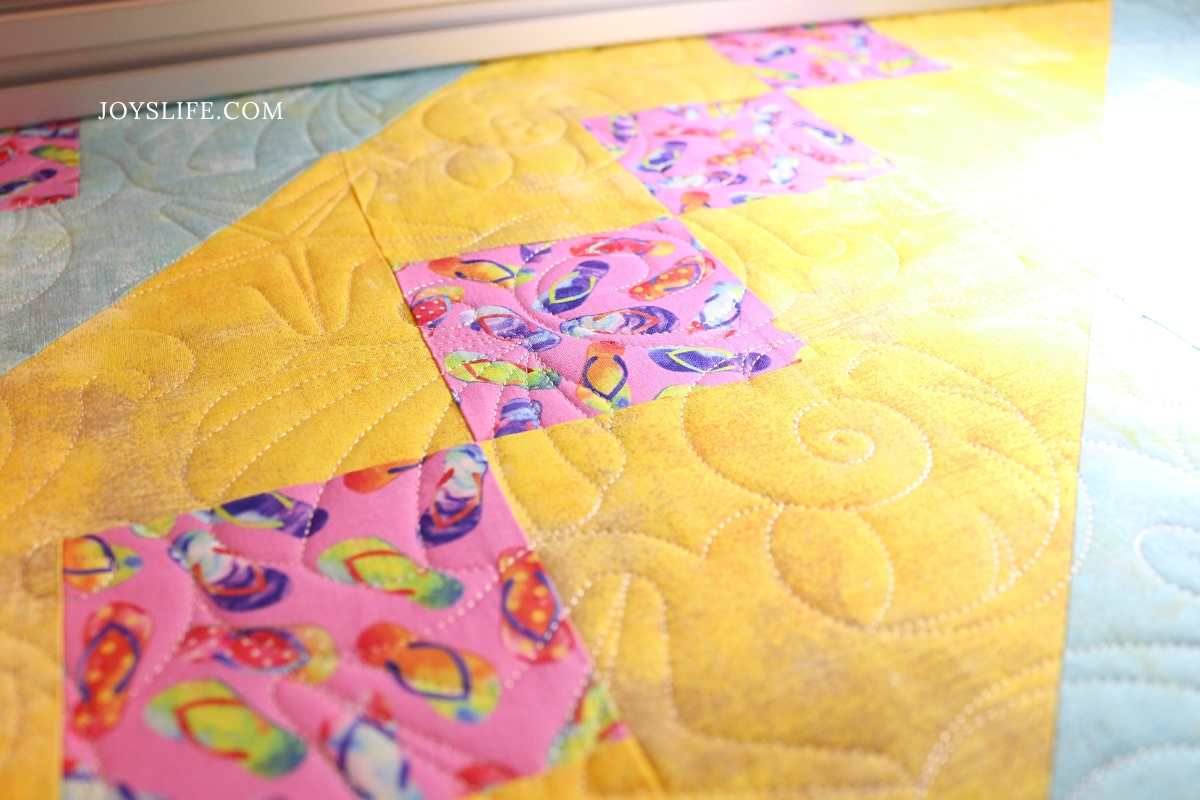 Colorful flip flop themed quilt with yellow background longarm quilted with seashells by Joy on a Bernina Q24 at joyslife.com