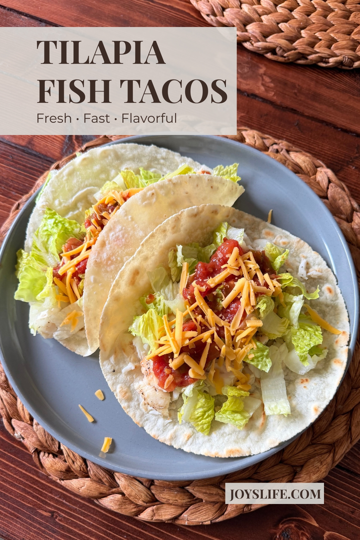 Tilapia fish tacos with lettuce, salsa, and shredded cheese on soft tortillas served on a plate.